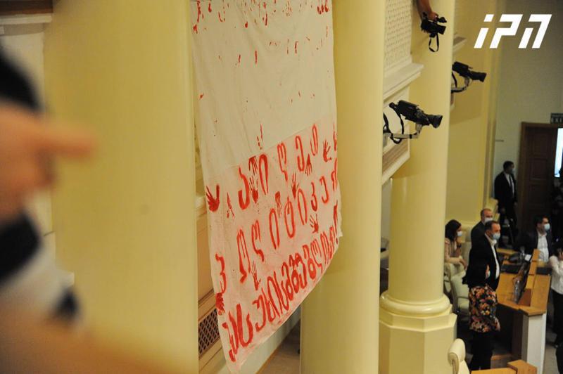 ირაკლი ზარქუა პარლამენტის სხდომათა დარბაზის აივანზე განთავსებულ მედიას, აივნიდან გადაფენილი ბანერების ჩამოხსნას სთხოვს