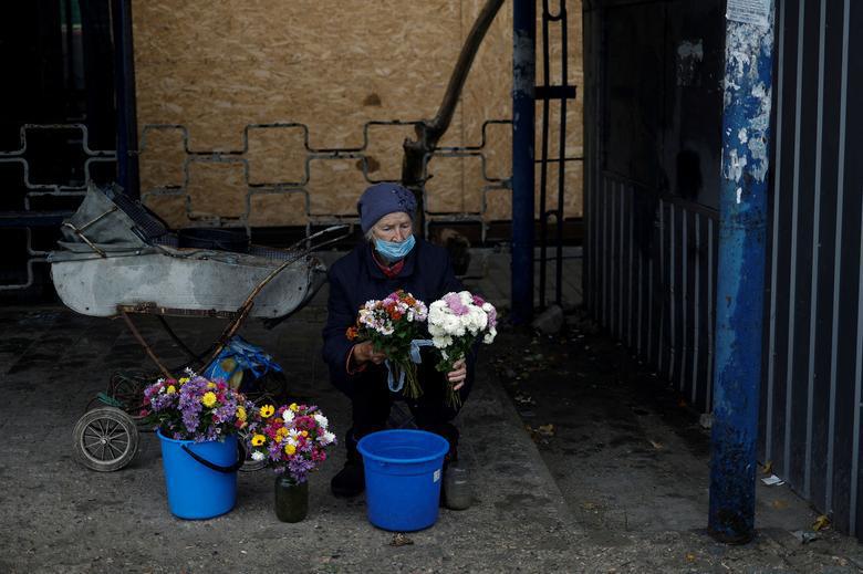 დღის ფოტო: რუსული სარაკეტო თავდასხმების ფონზე, მიკოლაევში, მოხუცი ქალი გაჩერებასთან ყვავილებს ყიდის