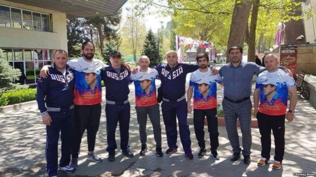 ქართველი მოჭიდავეები რუსეთის დროშის ფერებში შეკერილი მაისურებით, რომელზეც ჩრდილოეთ ოსეთის პარლამენტარია გამოსახული